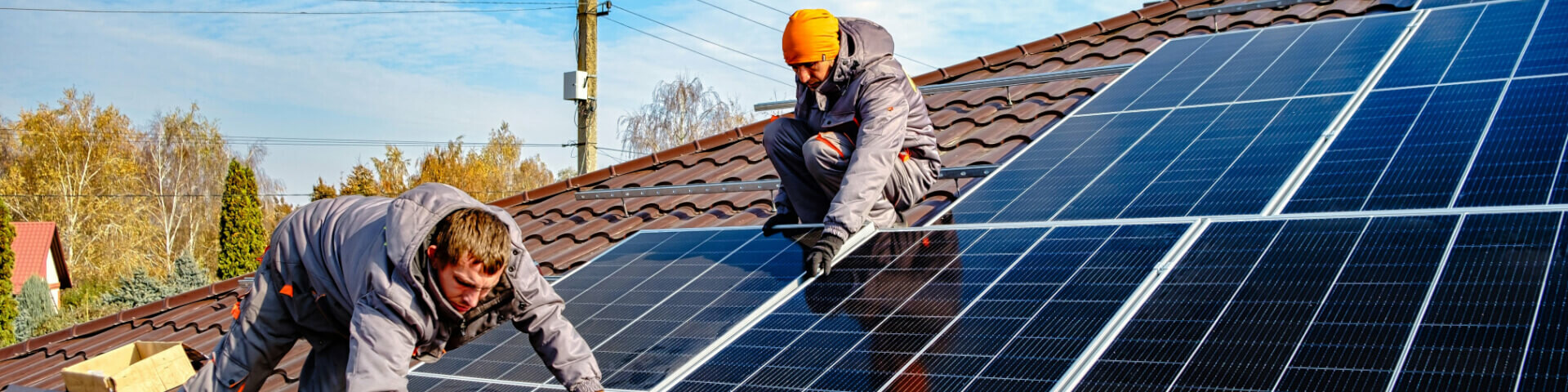 Zwei Männer arbeiten auf einem Hausdach und installieren Photovoltaik-Module.
