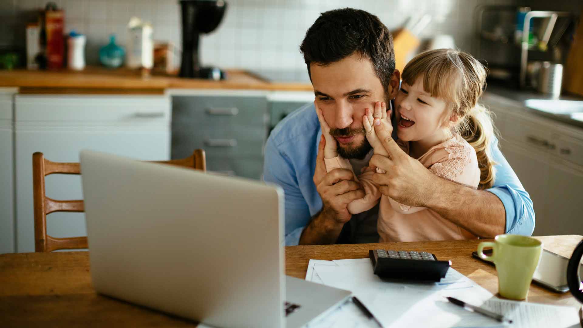 Vater und Tochter sitzen am Tisch vor einem Laptop