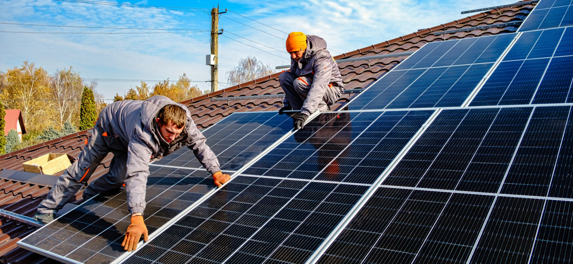 Zwei Männer arbeiten auf einem Hausdach und installieren Photovoltaik-Module.