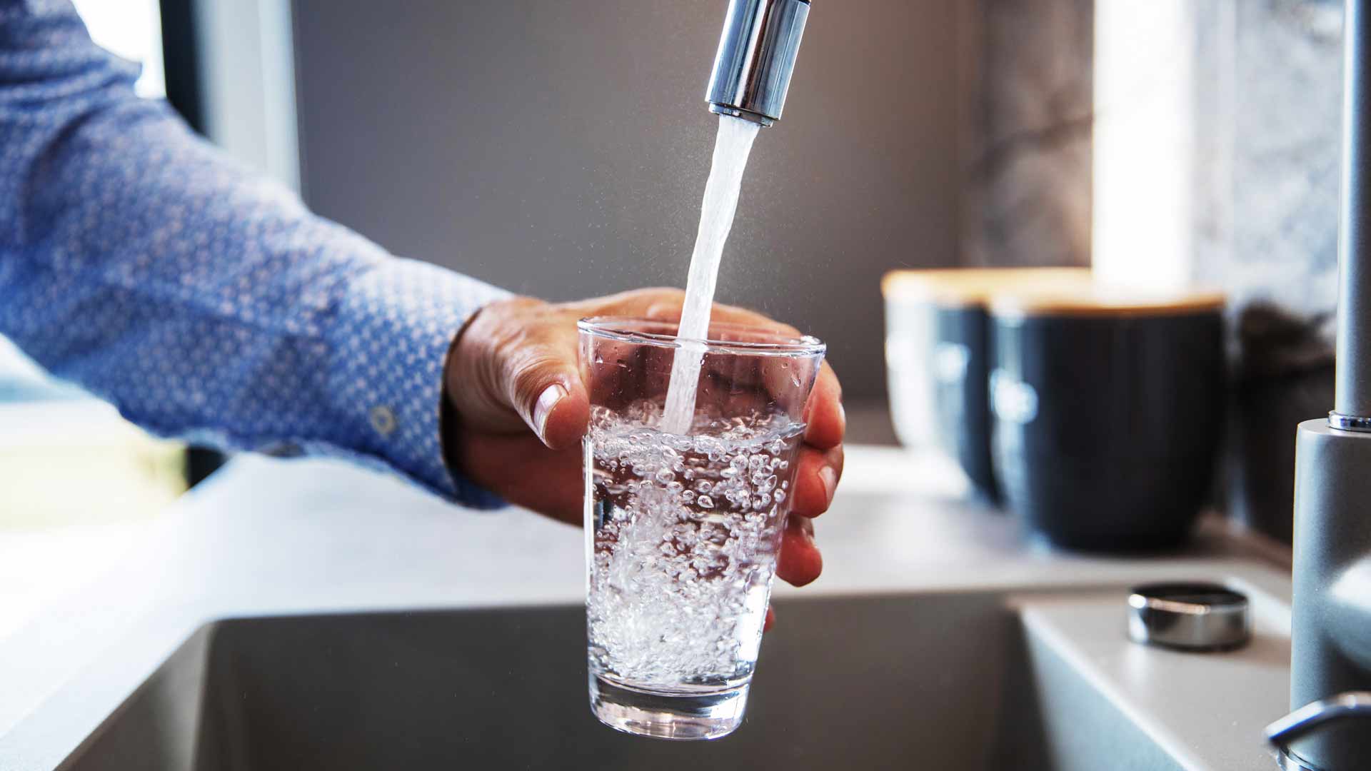 Wasser aus dem Wasserhahn fließt in ein Glas.
